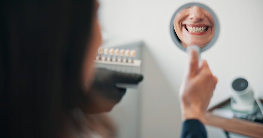 A woman admiring her smile after cosmetic dentistry treatment