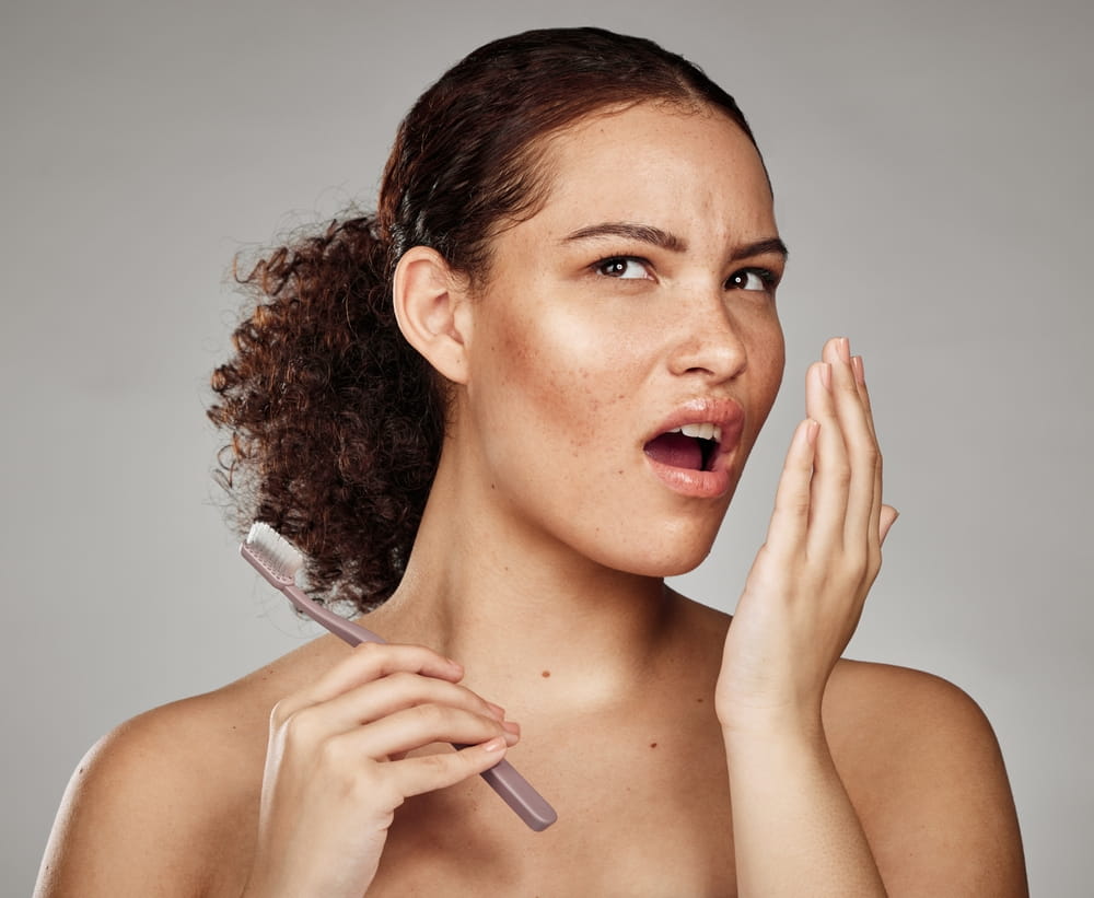 Une femme tient sa main devant sa bouche pour vérifier si elle a mauvaise haleine