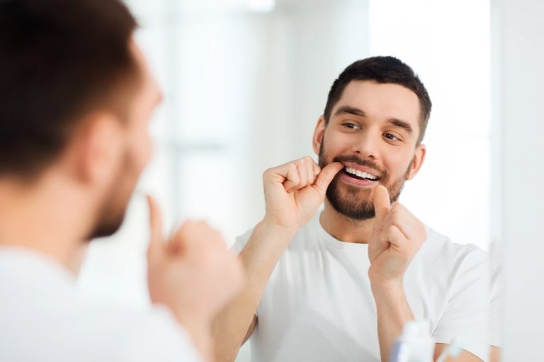 Young man flossing his teeth