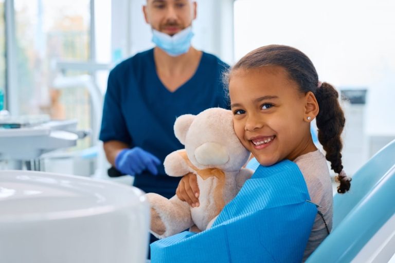 Little girl holding a teddy bear during her dental visit